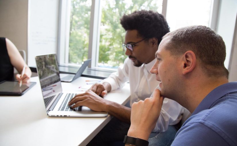 instructor helping student with programming work on laptop