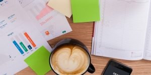 A cup of coffee on a desk with books and papers