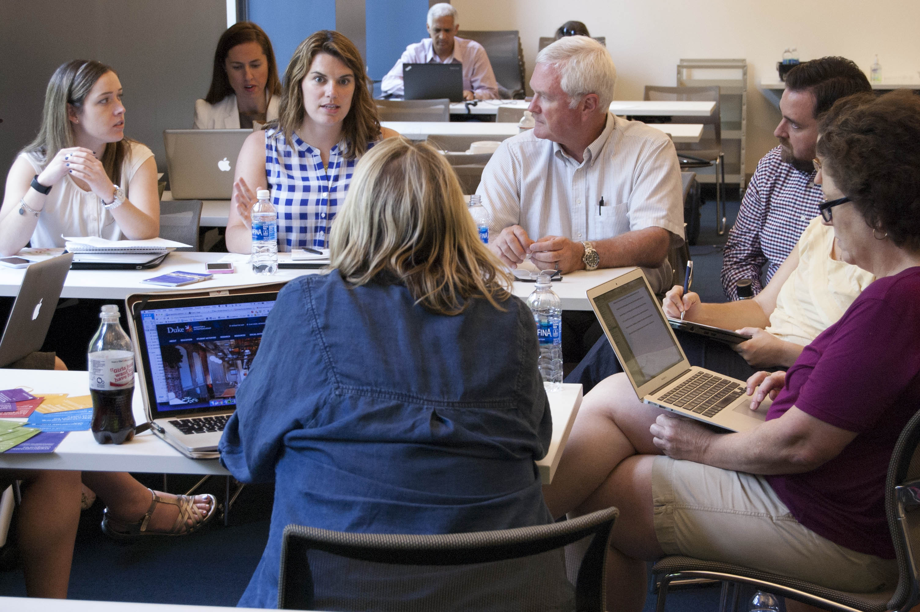 Group of faculty in discussion around table in classroom