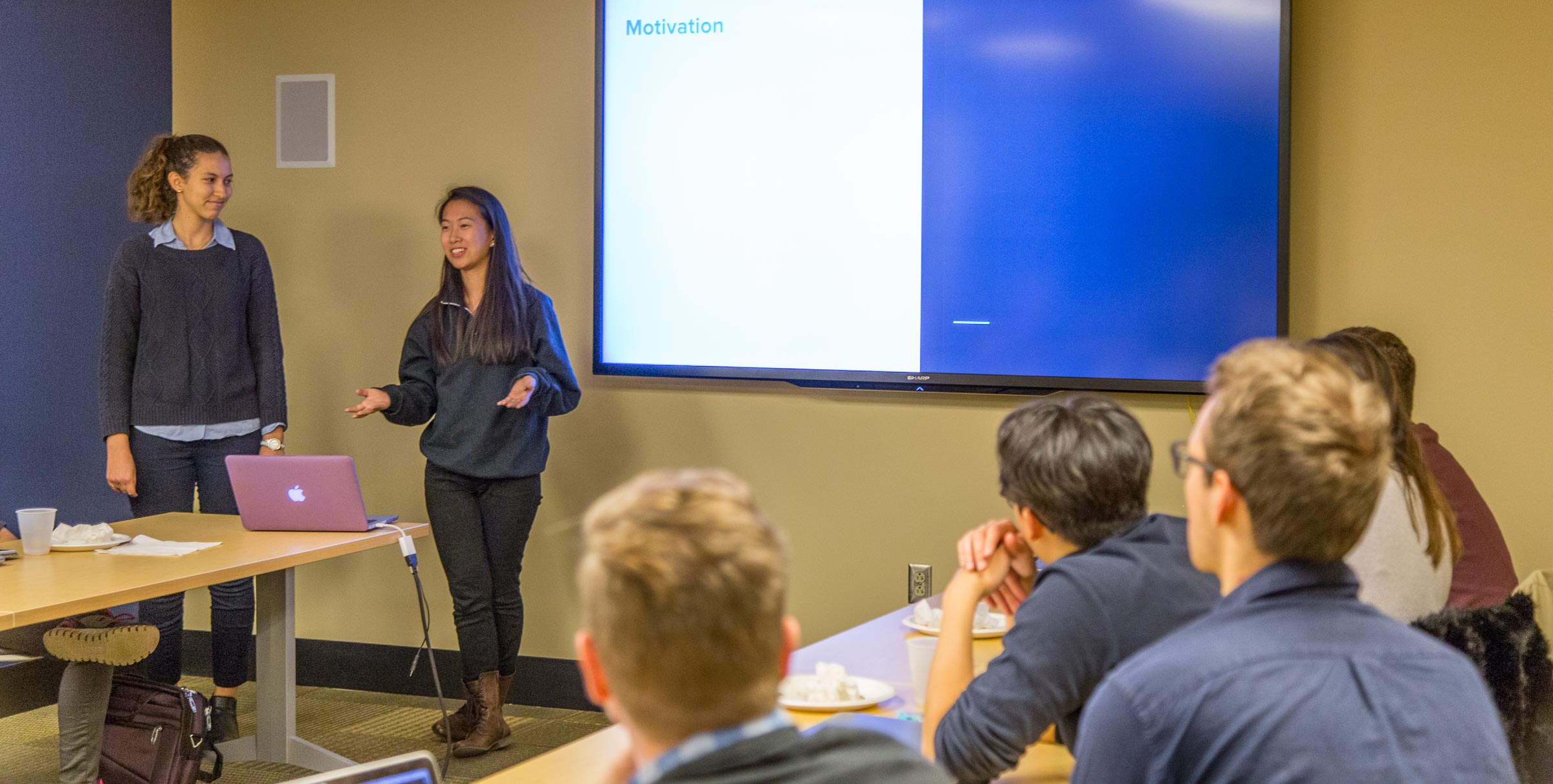 two students giving a presentation in front of a classroom