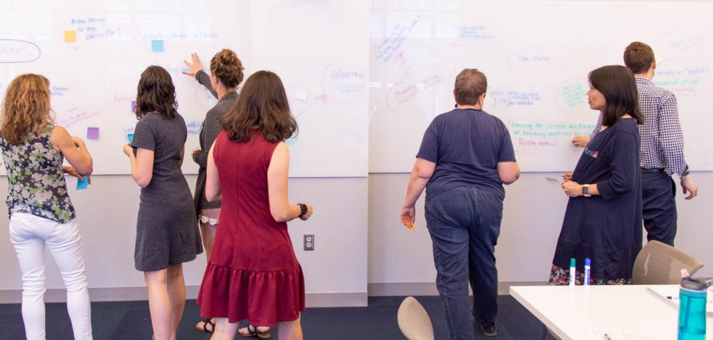 The Active Learning Fellows discussing ideas written on a board.