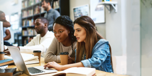 two people working at a laptop in a small classroom