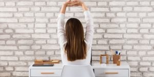 Rear View Of A Woman Stretching Her Arms at Desk