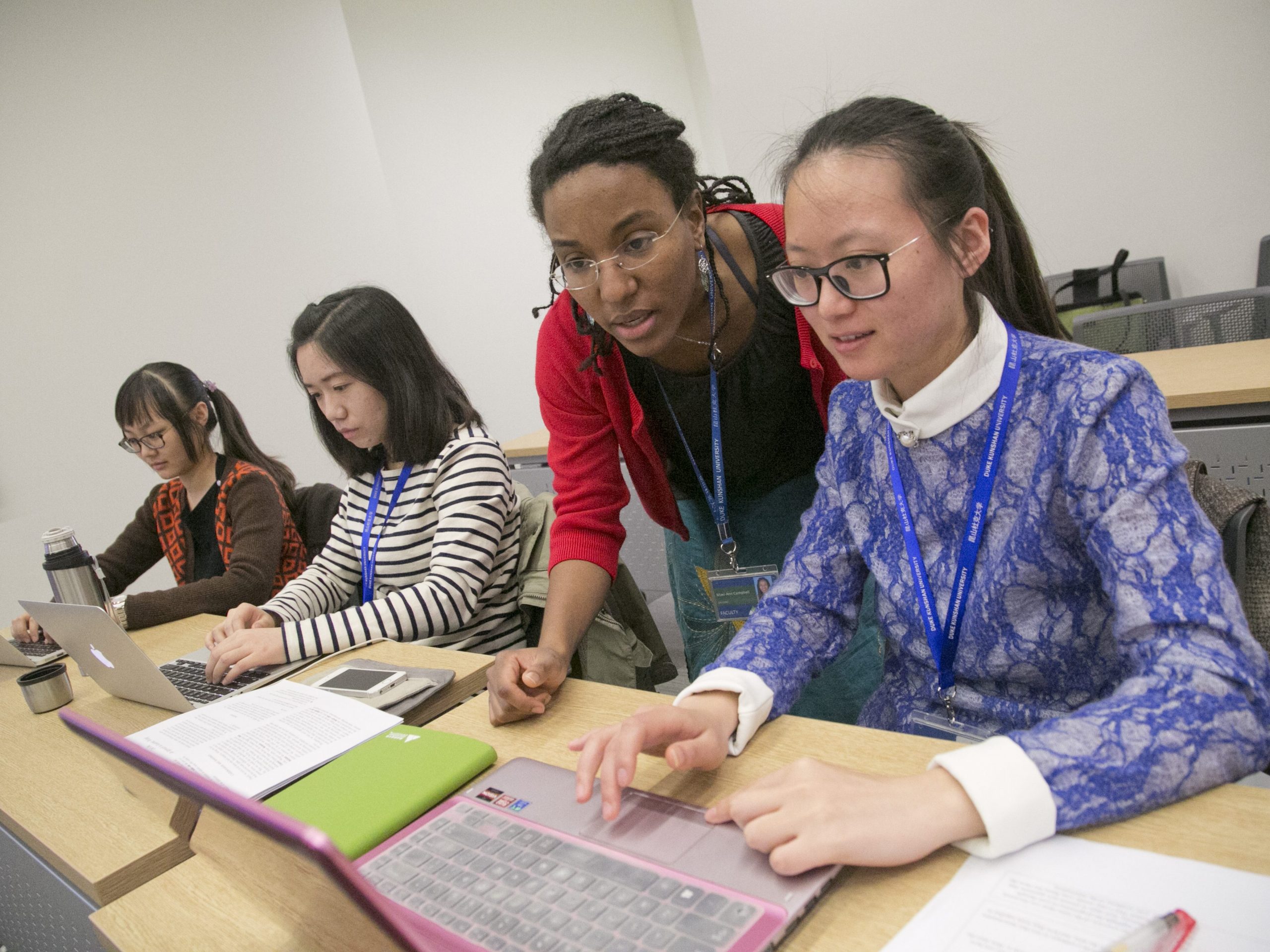 A DKU professor assists a student on her laptop.