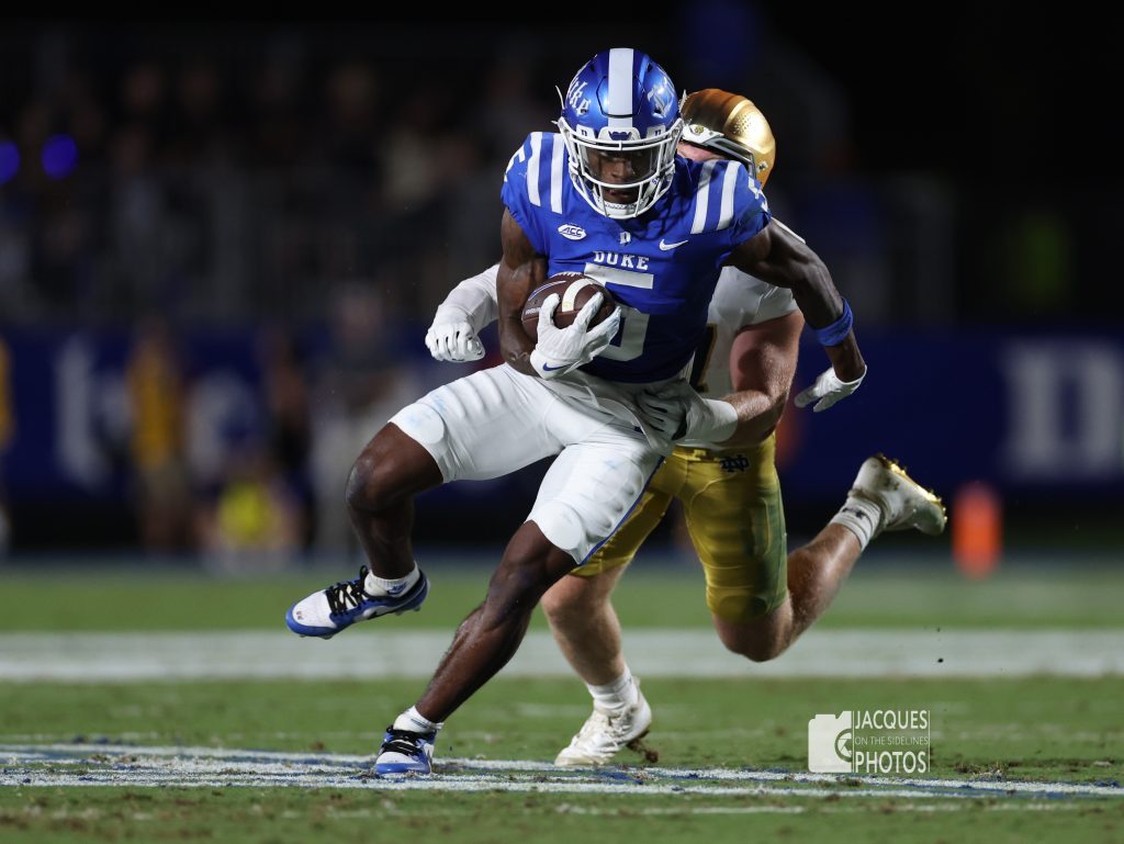 A Duke football player is tackled by an opponent.