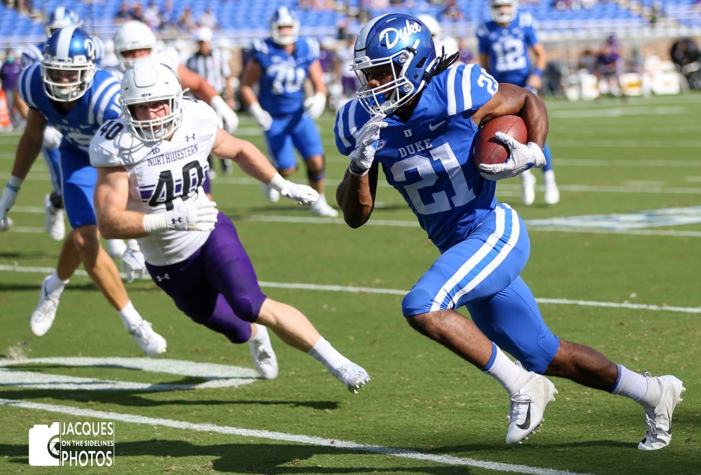 A Duke football player running past an opponent.